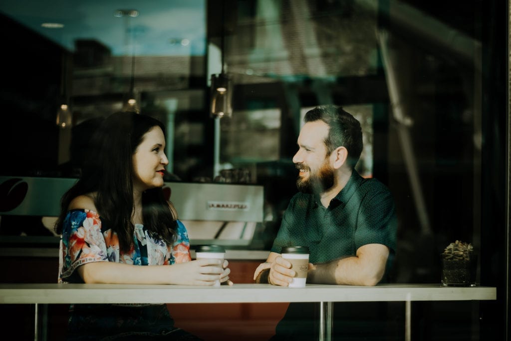 man and woman talk in coffee shop seen through window