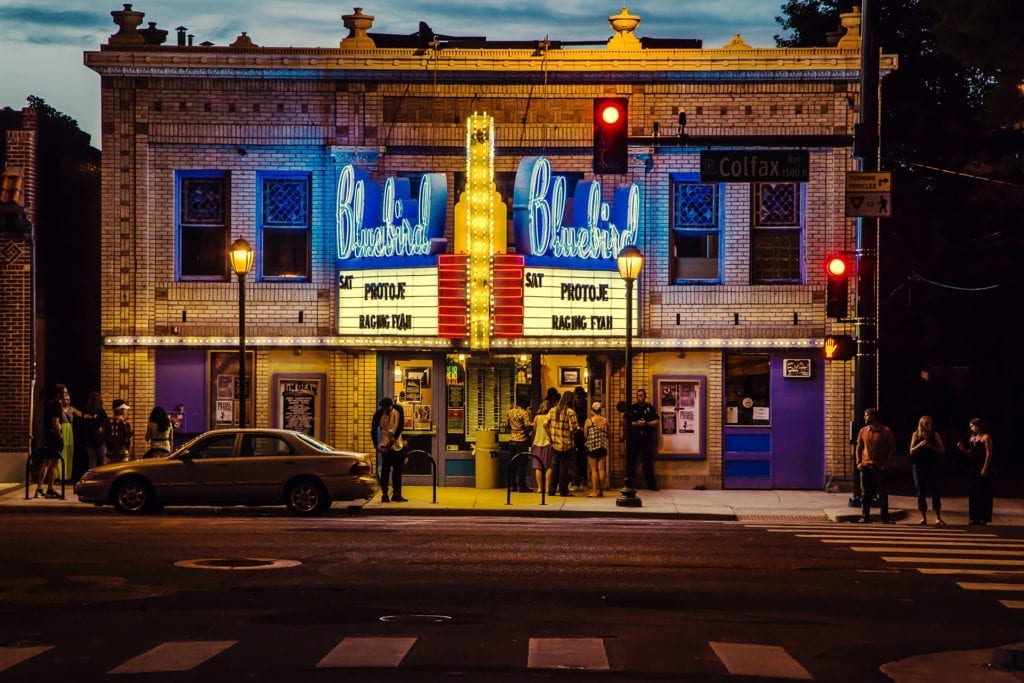 group of people waiting outside classic movie theatre marquee