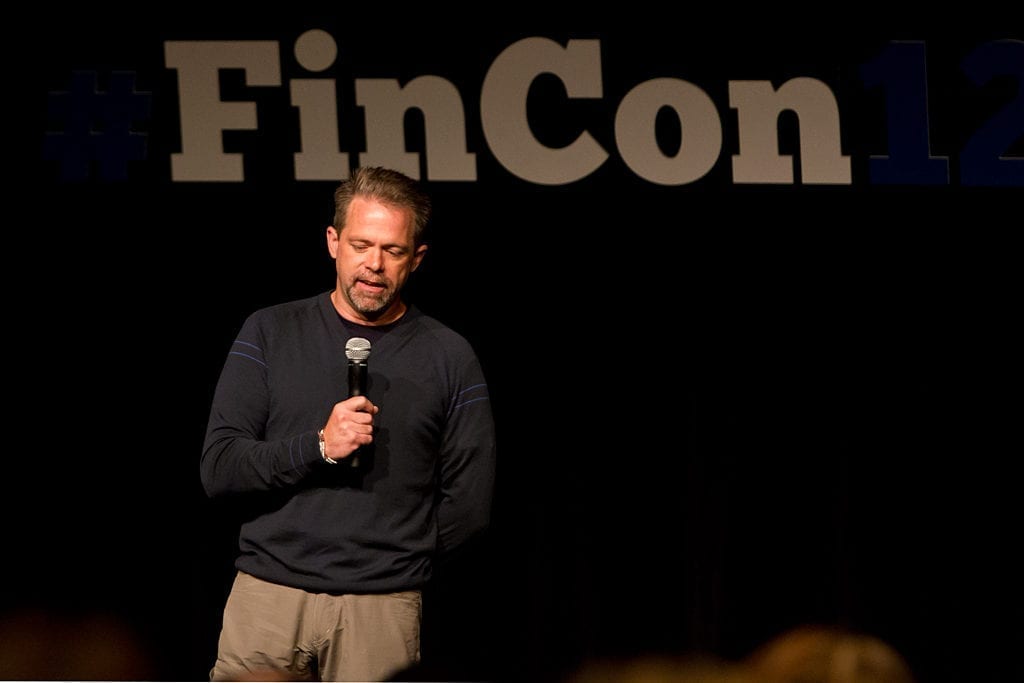 J.D. Roth talking to the FINCON crowd before the opening keynote man speaking at a conference on stage with microphone