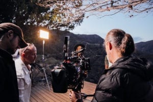 director and cinematographer view camera monitor on independent film set with lighting and sound recording equipment