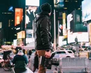 mN STANDS IN TIMES SQUARE WITH A RED CAMERA FILMMAKER