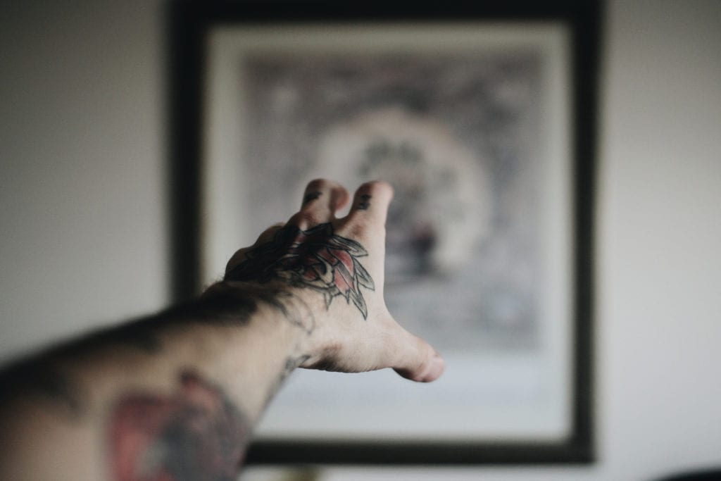 tattoo hand reaches toward painting point of view