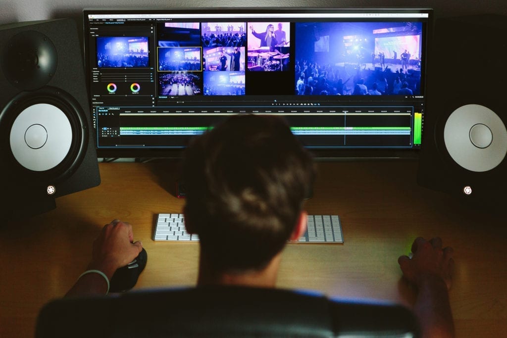 man sitting editing video with speakers