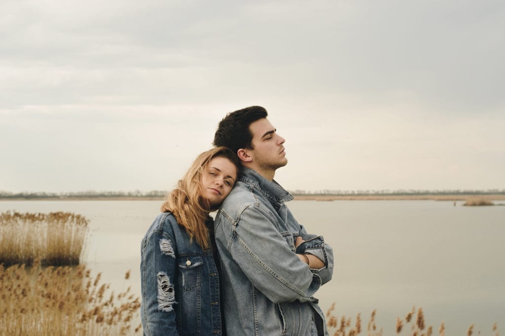 man and woman in denim jackets stand by bay