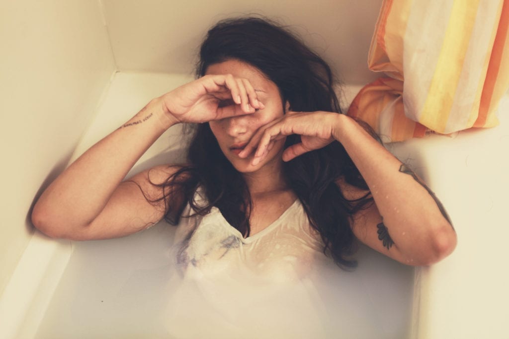 woman in bathtub overcome with emotion stressed