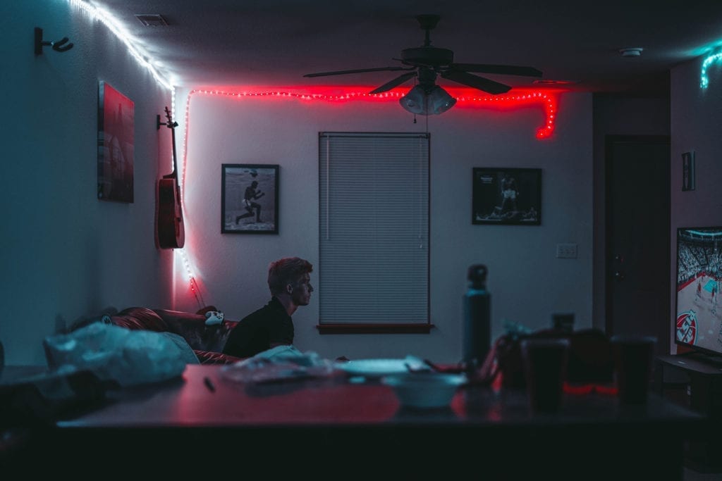 man sits in living room watching a movie