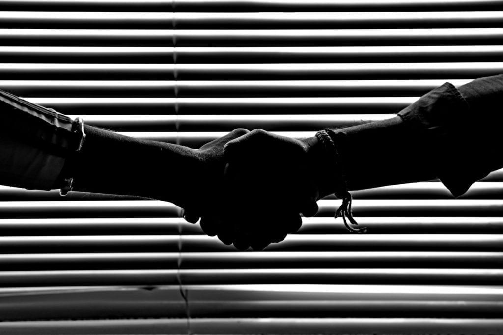 black and white handshake in front of window blinds