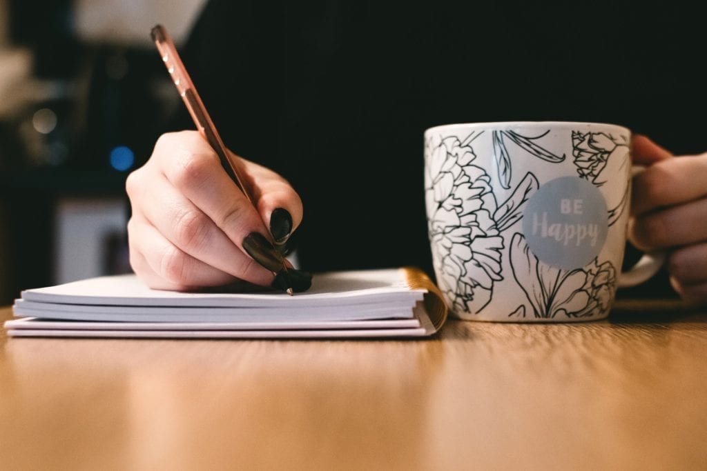 woman writing screenwriting notes with pen