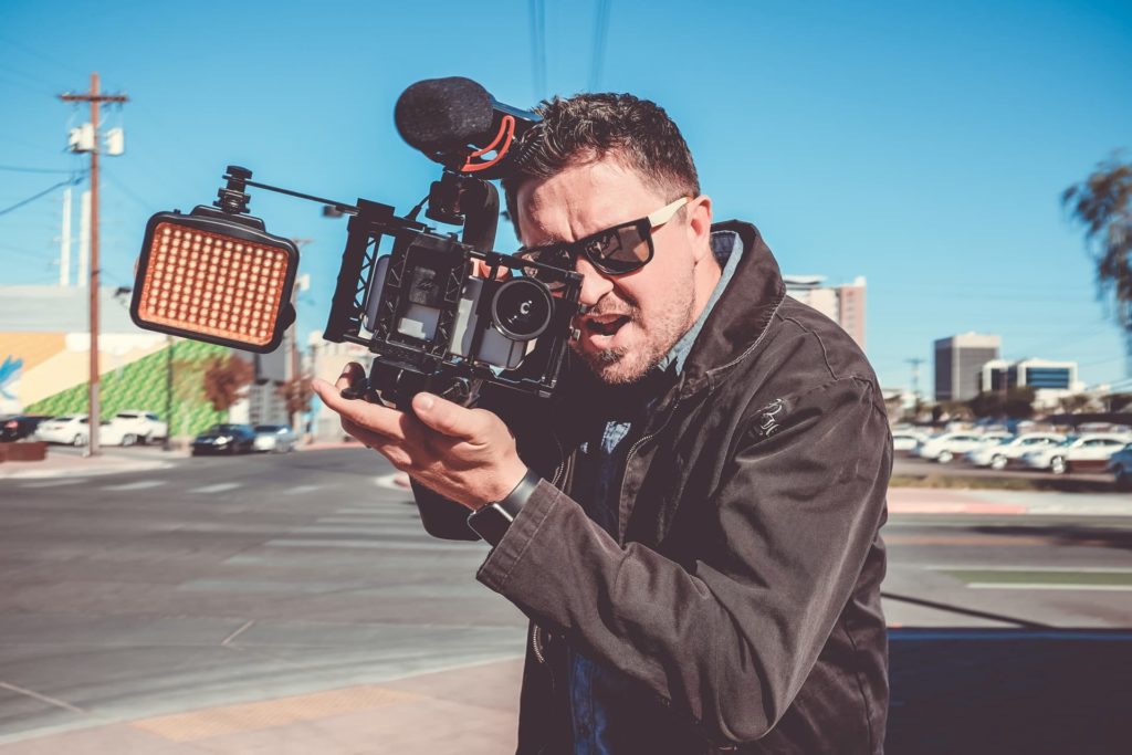 filmmaker holding camera wearing sunglasses