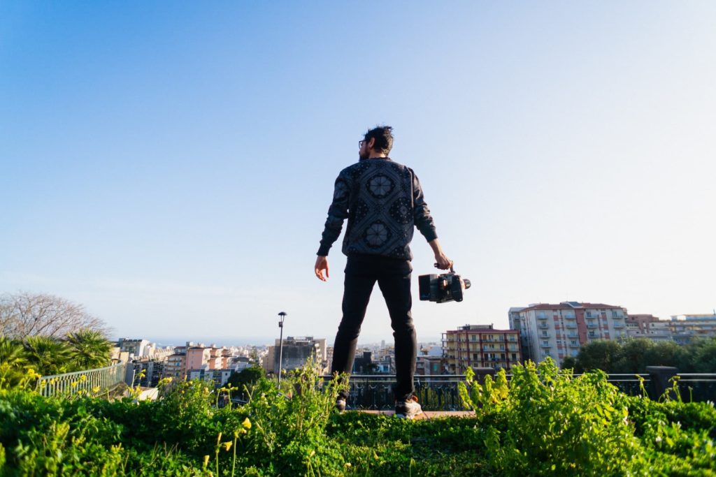 filmmaker holding camera on grassy hill