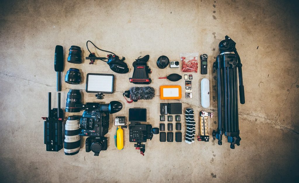 filmmaking equipment on floor tripod camera light microphone batteries lenses