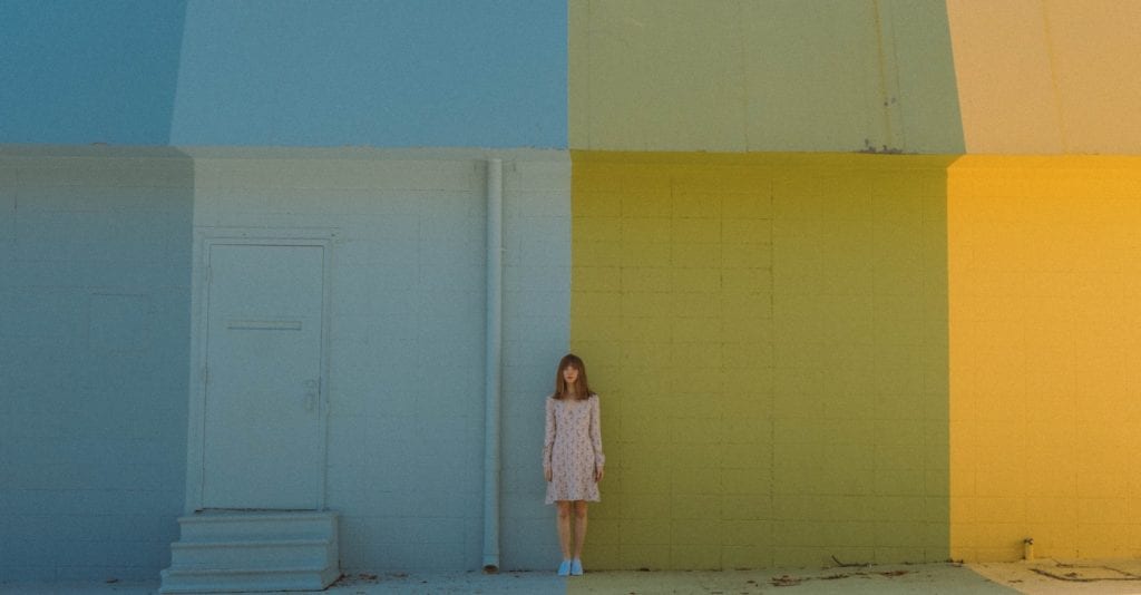 Woman standing in front of colored wall film fund.