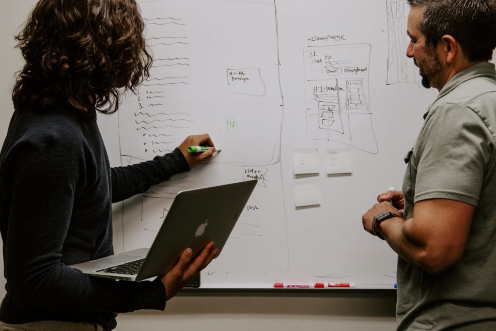 two individuals having a discussion by a white board the film fund