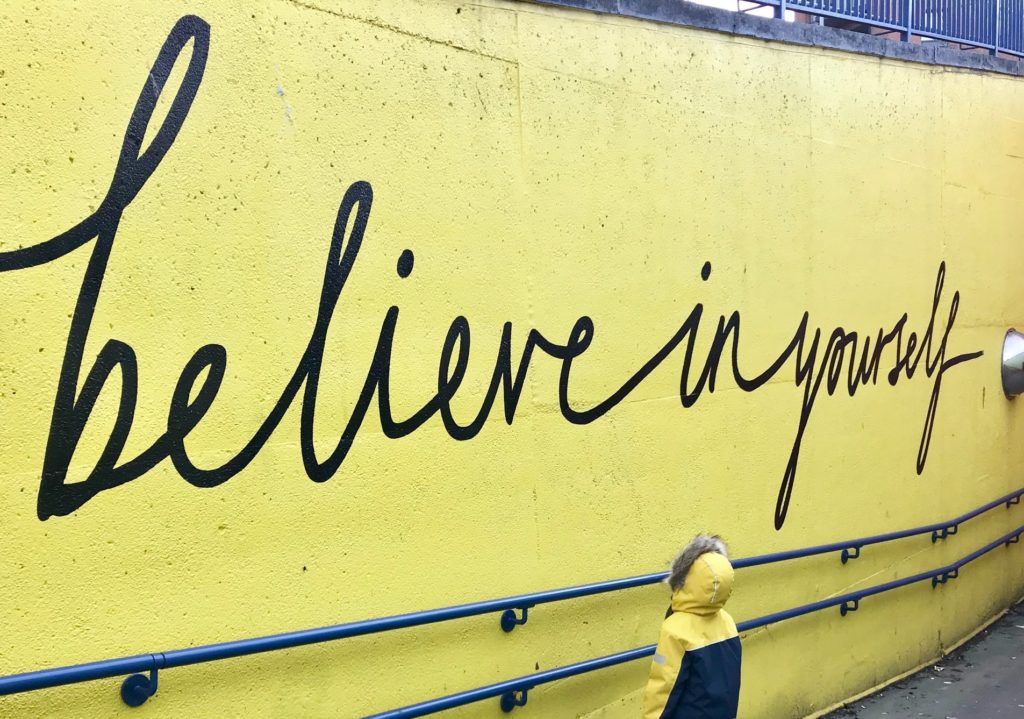 person standing in front of wall that says 'believe in yourself' the film fund