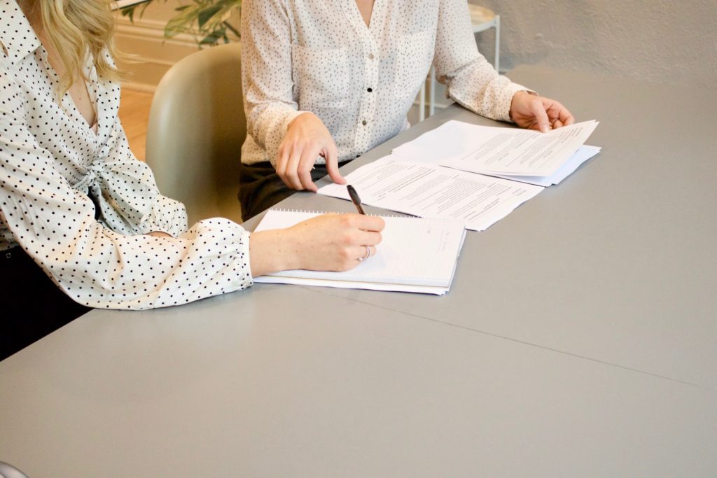 two people signing papers on desk the film fund